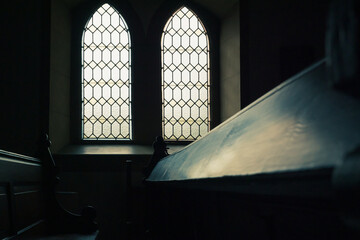 zwei Kirchenfenster mit Lichteinfall auf eine Holzbank
