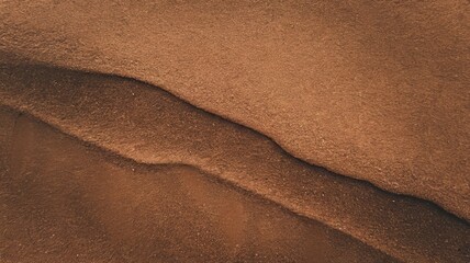 close-up view of textured sandy surface with natural ridges and rich brown hues