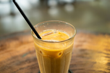 A close-up of an iced café latte with a straw on a table, showcasing its creamy layers and refreshing appearance