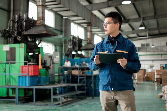 Middle-aged East Asian male blue-collar workers are using tablets in the factory