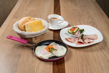 Hearty breakfast on a wooden table: Eggs bread ham salad and coffee provide a delicious meal