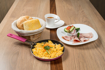Delicious breakfast assortment with eggs bread coffee ham and salad displayed on a wooden table