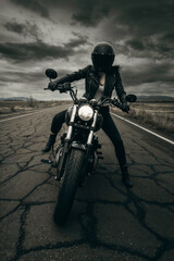 Obraz premium Brunette Woman in Black Leather Riding a Motorcycle on a Cracked and Isolated Apocalyptic Road, Beneath a Moody Cloudy Sky, Her Presence Radiating Power, Freedom, and Resilience.