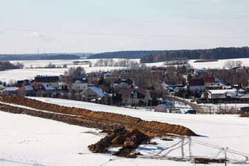 Road construction. Excavator digs a trench for laying a sewer pipe on a cloudy winter day. Selective focus, shallow depth of field