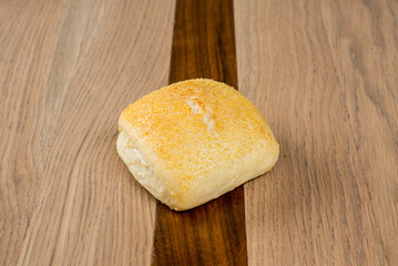 Freshly baked dinner roll with a golden brown crust on rustic wooden surface A simple delicious side