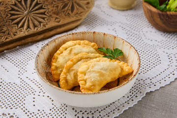 Rustic Presentation of Mini Chebureki Pastries in Earthy Tones with Intricate Textural Details