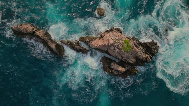 Drone view of jagged rock formations and crashing waves from above at Sharks Teeth Beach