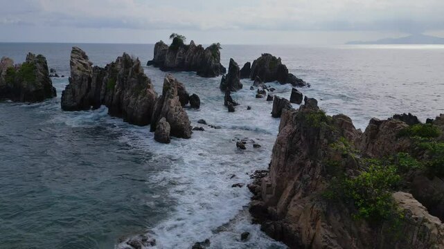 Drone aerial view of Sharks Teeth Beach with its jagged rock formations and crashing waves at sunset