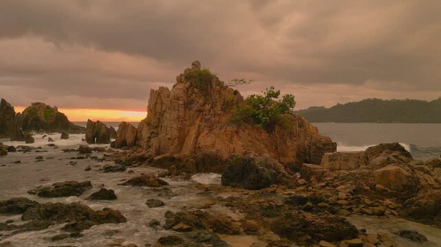 Drone aerial view of Sharks Teeth Beach with its jagged rock formations and crashing waves at sunset