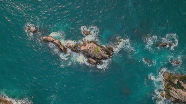 Drone top-down view of jagged rock formations and crashing waves from above at Sharks Teeth Beach