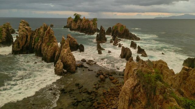 Drone aerial view of Sharks Teeth Beach with its jagged rock formations and crashing waves at sunset