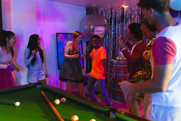 Diverse teen friends dancing and laughing at home party with pool table and disco ball © WavebreakMediaMicro