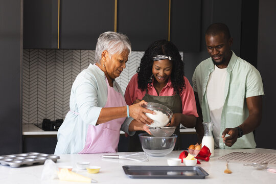 Three diverse generations baking in kitchen, sharing joy and diverse family traditions, at home