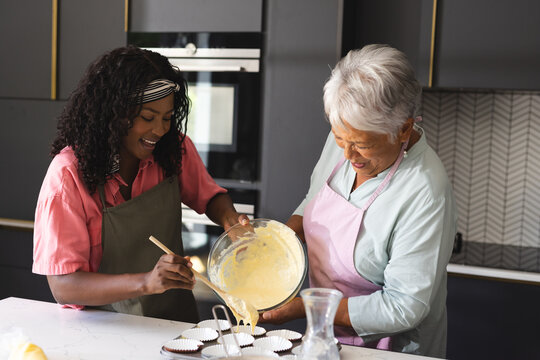 Baking cupcakes, diverse grandmother and child sharing joyful moments in kitchen, at home