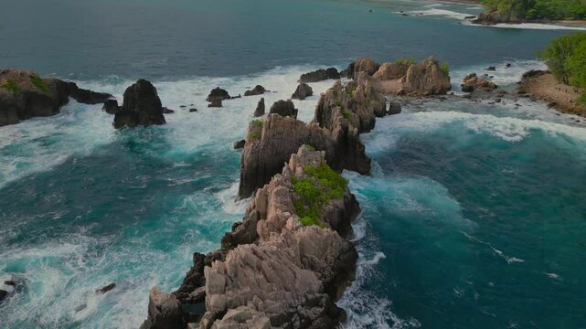 Aerial view of jagged rock formations and crashing waves on Sharks Teeth Beach of Indonesia
