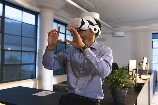 Businessman using VR headset in modern office, exploring virtual environment