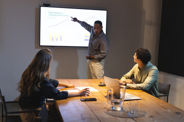 Financial graphs, professional diverse team in business meeting at night conference room, at office
