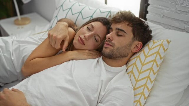 Couple in love relaxing on a bed in a cozy home bedroom, embracing each other peacefully with closed eyes, exemplifying warmth and intimacy.
