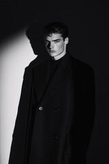Obraz premium Dramatic High-Contrast Portrait of a Male Model in Moody Lighting, Featuring Fashion Aesthetics with Strong Shadows and Bold Color Accents