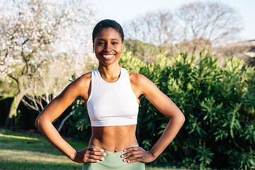 Young black woman smiling and posing after exercising outdoors in a park