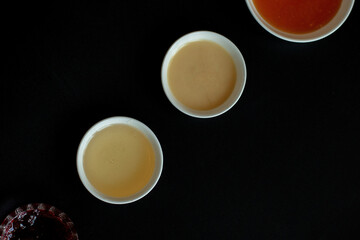 red currant jam and honey in bowls on the black background