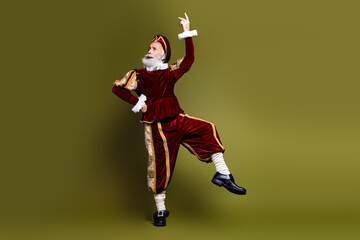Mature man in royal costume posing in a historical outfit against a khaki background, exploring a...