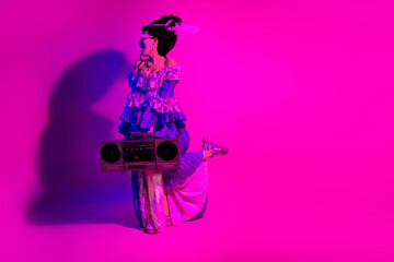Royal themed retro style woman posing with vintage boombox against ultraviolet neon pink background...