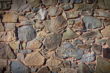 Textured stone wall showcasing natural hues and shapes from centuries of craftsmanship in a rustic setting
