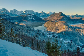 View of snowy mountain landscape with lake and mountains near Neuschwanstein Castle, capturing early morning light in beautiful winter area, showcasing detailed high-quality photograph of icy