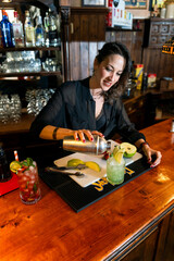 Bartender pouring cocktail from shaker into glass on bar counter