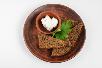 Traditional rural dish with slices of dark rye bread, spread with lard and fresh parsley on a ceramic plate. Authentic Eastern European cuisine close-up, top view, side view