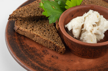 Traditional rural dish with slices of dark rye bread, spread with lard and fresh parsley on a ceramic plate. Authentic Eastern European cuisine close-up, top view, side view