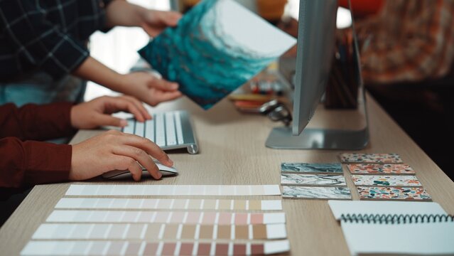 A dynamic creative workspace showcasing hands of designers collaborating on a project with color palettes, mood boards, and digital tools arranged for inspiration. SACTR