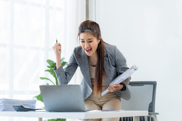 Triumphant Woman in the Office: An excited businesswoman celebrates a success in a modern office space. Capturing her excitement and accomplishment.