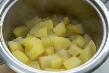 Boiled potatoes in a stainless steel pot, close-up.