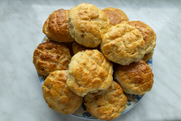 Homemade golden brown scones on a plate on a marble surface.