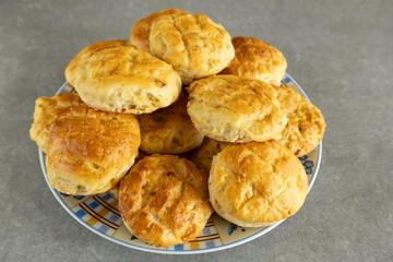 Homemade golden brown scones on a plate on a gray surface.