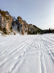 The snowy road, blanketed in white, has tire tracks weaving through the fresh snow, showcasing recent vehicle passage in this beautiful winter scene that highlights natures beauty