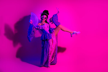 Elegant young woman in regal costume dancing in vibrant neon lighting with modern twist