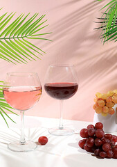 Modern still life with glasses of white and red wine, alcoholic cocktail Margarita and grapes on background with long hard shadows, minimalist concept for bar, cafe, advertising banner,