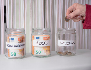 Domestic control of monthly expenses. Some glass jars labeled with money inside for expenses.
