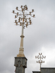 Lighting fixtures on the street. Openwork lanterns. Cloudy sky.