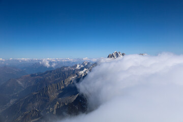 View of the French Alps with a blue sky and clouds covering the peaks above 3000 m above sea level