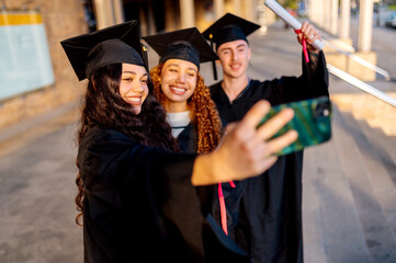 Multiracial group of students taking a selfie with smartphone on their graduation day