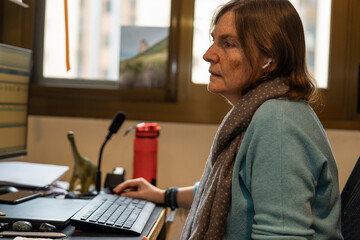 Focused paleontologist wearing earphones and using computer keyboard while working from home