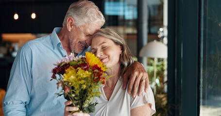 Hug, flowers and senior couple in home for romantic surprise, celebration or gift in morning. Happy, love and elderly male person with floral bouquet present for wife on valentines day at house.
