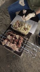 Cook preparing skewers of meat shashlik and onions for grilling in prague summer day
