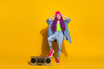 Fashionable Young Woman in Denim Outfit Against a Bright Yellow Wall