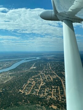 aerial view of okavango delta and kasane town during airplane takeoff from kasane airport, botswana. green african landscape with river channels, nature, and village seen from small aircraft window in