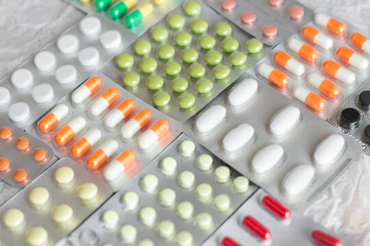 Big pharma metal tablet blister. Multicolor pills medicine. Silver shiny blister with drugs. Transparent capsules in blister pack closeup. - Powered by Adobe